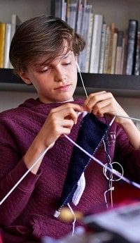 Adolescent qui essaie le tricot